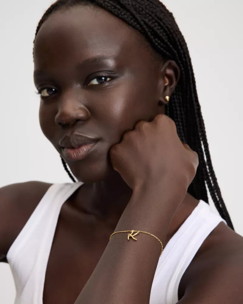 pulseira dourada com inicial em estilo cursivo